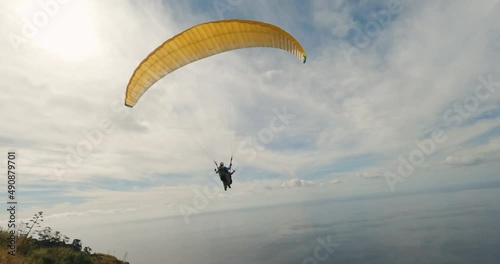 FPV drone over the mountains and the sea following a paraglider