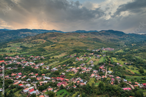 Aerial view in a rural area on a village in Romania with mountains and hill at sunset © Cristi