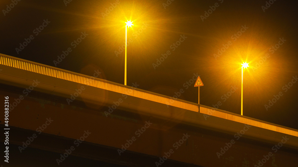 Vue rapprochée d'un pont enjambant une zone portuaire, à Port-La-Nouvelle.  L'éclairage nocturne crée de la réfraction sur l'image