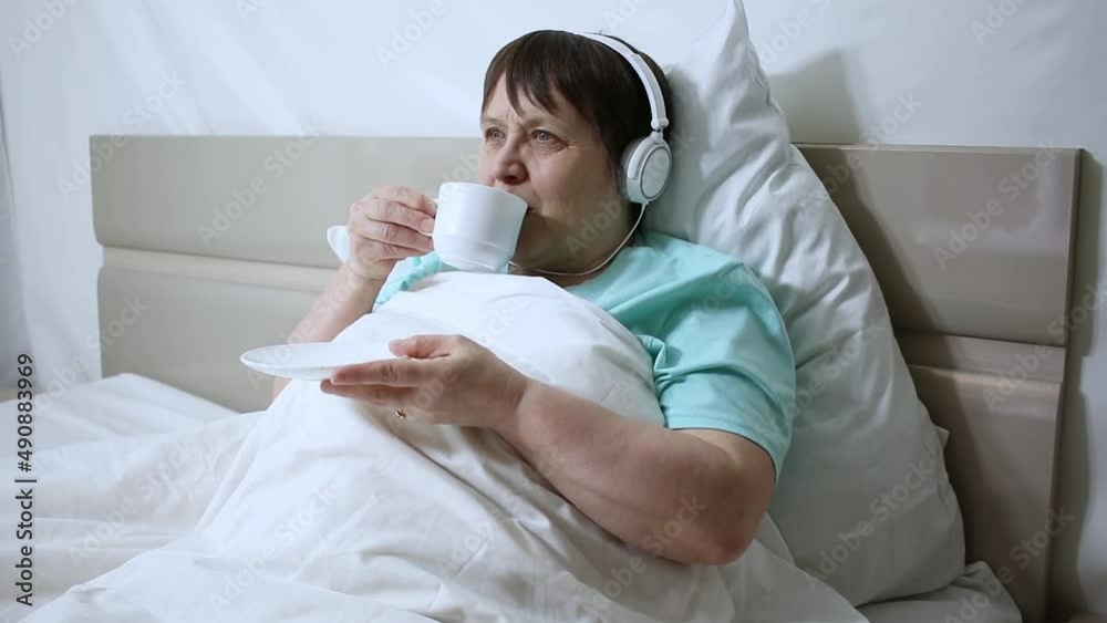 Morning coffee for grandma. An elderly woman with headphones listens to music and drinks coffee. Morning coffee for grandma. An elderly woman with headphones listens to music and drinks coffee.
