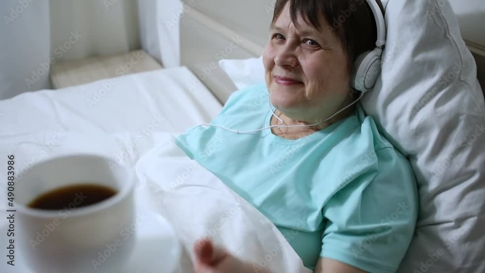 Morning coffee for grandma. An elderly woman with headphones listens to music and drinks coffee. Morning coffee for grandma. An elderly woman with headphones listens to music and drinks coffee.