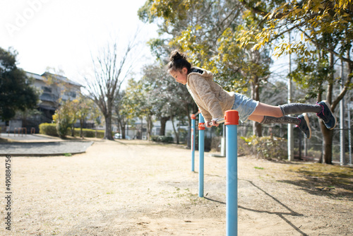Fototapeta Naklejka Na Ścianę i Meble -  公園の鉄棒で遊ぶ女の子