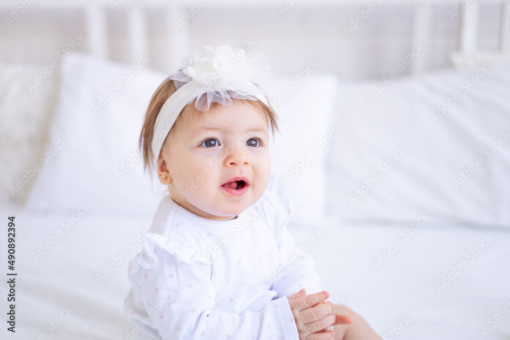 a large portrait of a cute and joyful baby girl in a crib in white clothes, a funny little child at home, the concept of children's goods a large portrait of a cute and joyful baby girl in a crib in white clothes, a funny little child at home, the concept of children's goods
