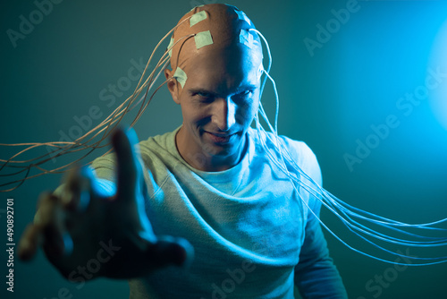 scary young man with his head entangled in wires, uses mind control and telekinesis, electrical contacts on his bald head, signals to the brain. Neurointerface, future technologies, creative concept. photo