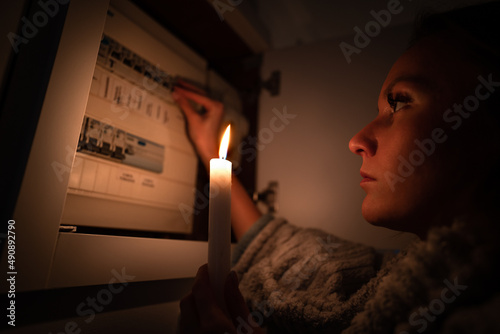 Woman checking fuse box at home during power outage or blackout. No electricity concept photo