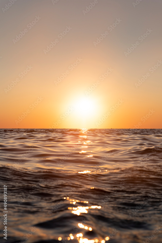 Sunset with yellow sun at the horizon at sea