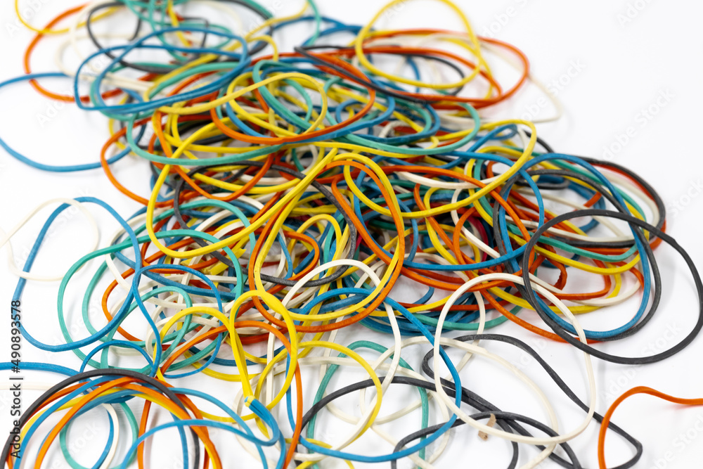 A lot of colored stationery rubber bands of yellow blue red green colors lie in a pile on a white background close-up A lot of colored stationery rubber bands of yellow blue red green colors lie in a pile on a white background close-up