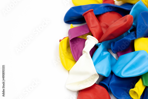 Multi-colored uninflated balloons lie in a pile on a white background on the right