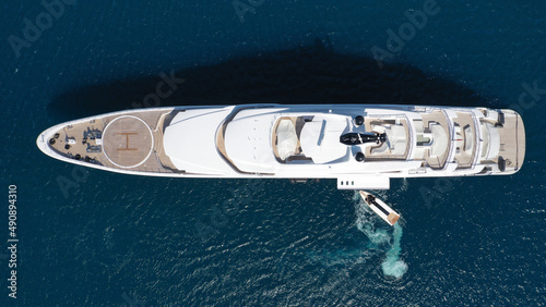 Aerial drone top down photo of large yacht with wooden deck anchored in Aegean island deep blue sea © aerial-drone