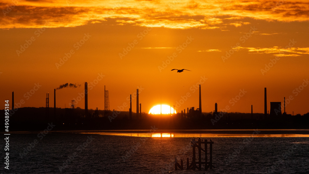 Global Warming Climate Change Concept Epic sunrise at Stanlow Oil Refinery and power plant on the Mersey Estuary Wirral. Greenhouse gas emissions and pollution warm the planet on an industrial dawn.