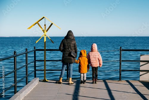 Mom with children looks at the sea from the pier
