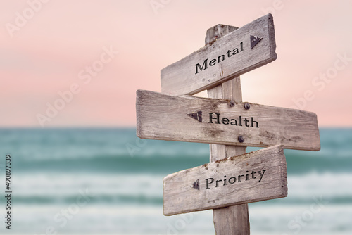 mental health priority text quote written on wooden signpost by the sea. Positive pink turqoise pastel theme.