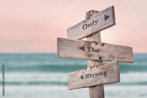only the strong text quote written on wooden signpost by the sea. Positive pink turqoise pastel theme.
