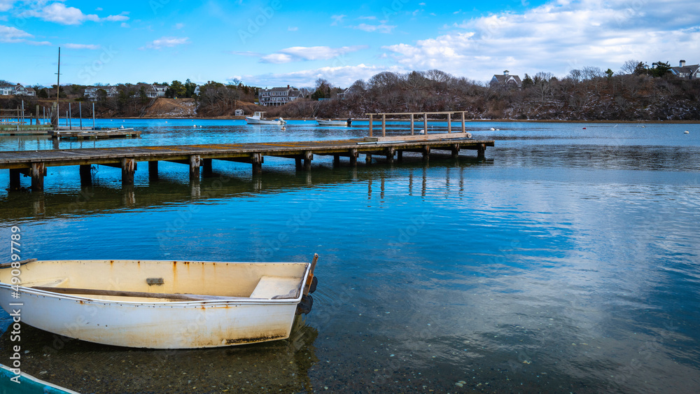 An empty old white dinghy at the pier. Idyllic seascape on a cloudy day on Cape Cod, Massachusetts.