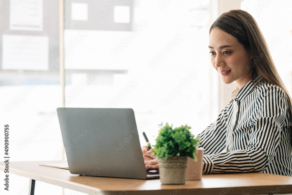 Portrait charming asian woman working with laptop and taking note on notepad. Portrait charming asian woman working with laptop and taking note on notepad.