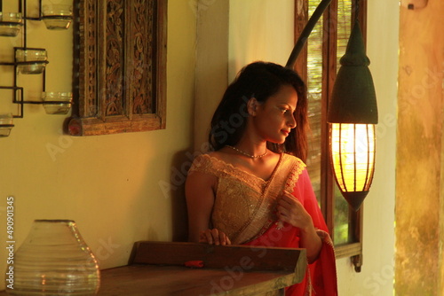 A charming young woman in a traditional red and yellow dress with a gold embroidered sari