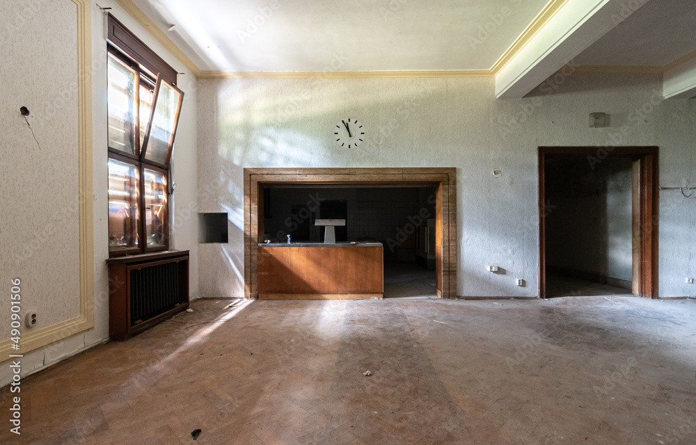 Fototapeta premium Old abandoned and run-down lobby or space of a theater with a clock against the wall and a window with light entering