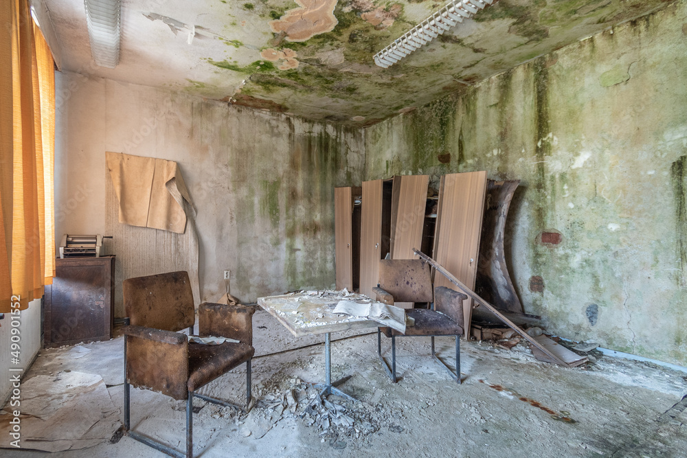 Old abandoned and run-down room in a hotel with destroyed chairs, table and closet Old abandoned and run-down room in a hotel with destroyed chairs, table and closet