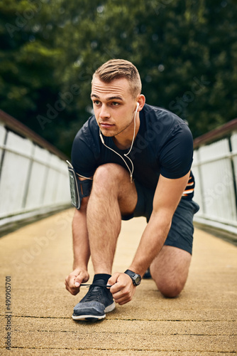 Get ready to run your heart out. Shot of a sporty young man tying his shoelaces while exercising outdoors.
