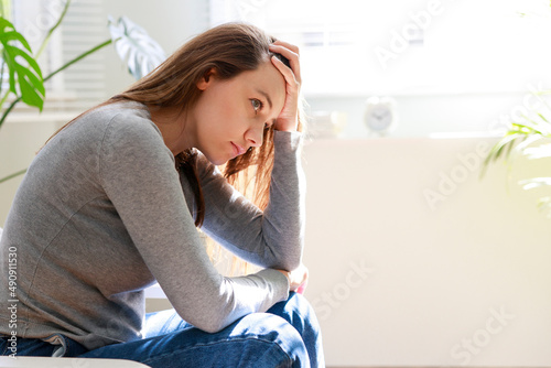 Fotografía Upset young woman sitting on couch alone at home