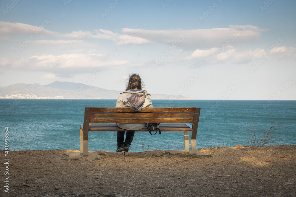Woman sitting on a bench looking relaxed at the sea on the Costa Brava Woman sitting on a bench looking relaxed at the sea on the Costa Brava