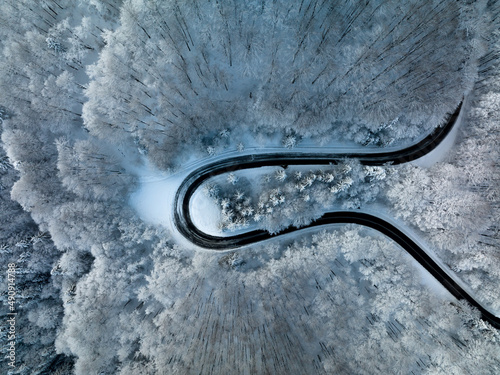 Mountain twisted winding road in winter shoot from above drone aerial view trees covered in snow