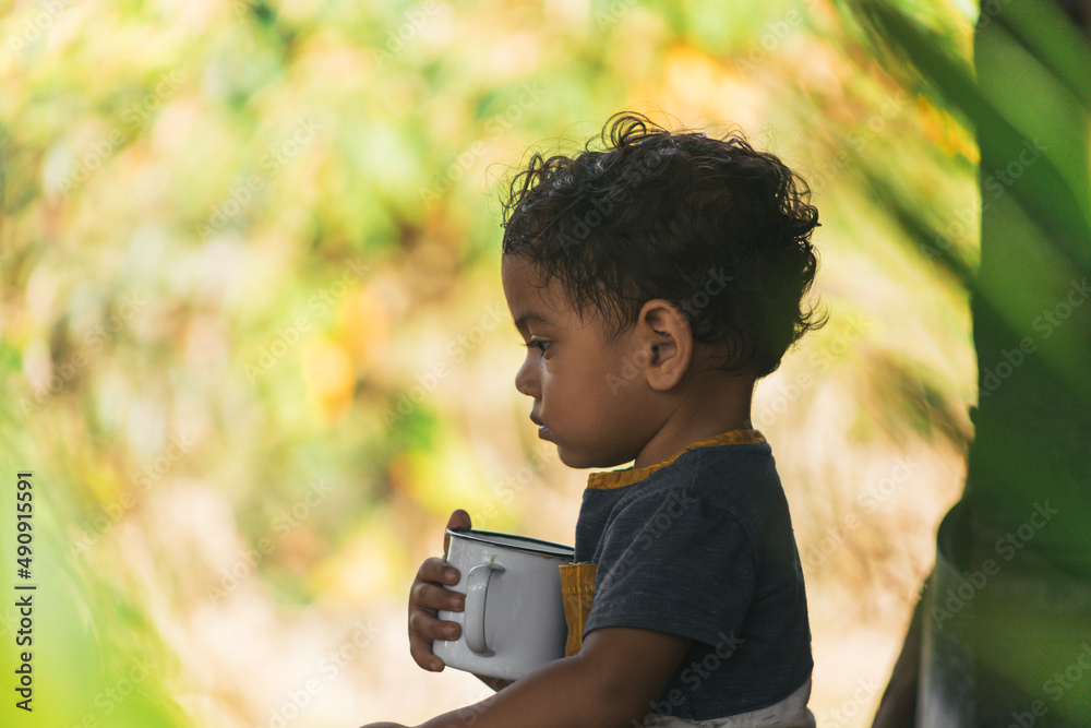 Fototapeta premium latin boy drinking coffee in a white cup, in a natural environment