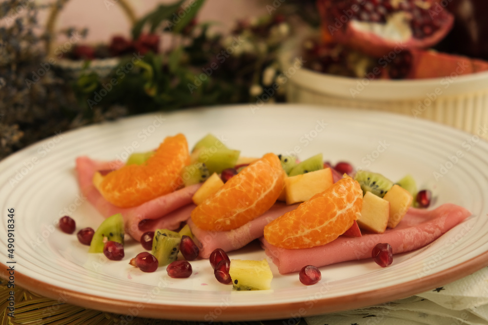 Pancakes. Pink sweet dough with fruits and honey. Tangerines, kiwi, pomegranate seeds. Floral background. Delicious breakfast at home or in a cafe. Selective focus. Shrovetide menu. carnival baking Pancakes. Pink sweet dough with fruits and honey. Tangerines, kiwi, pomegranate seeds. Floral background. Delicious breakfast at home or in a cafe. Selective focus. Shrovetide menu. carnival baking