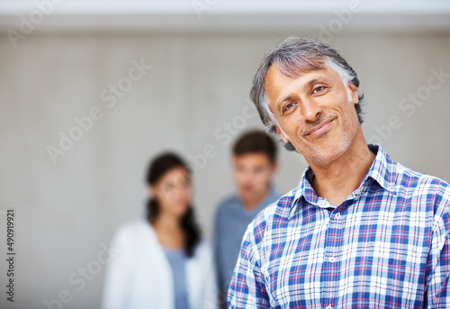 Mature architect with couple in background. Portrait of mature architect smiling with couple in background.