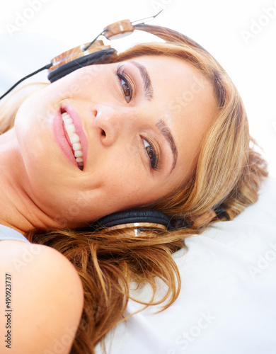 Relaxing with some great sounds. Young woman listening to music while wearing a pair of headphones and smiling.