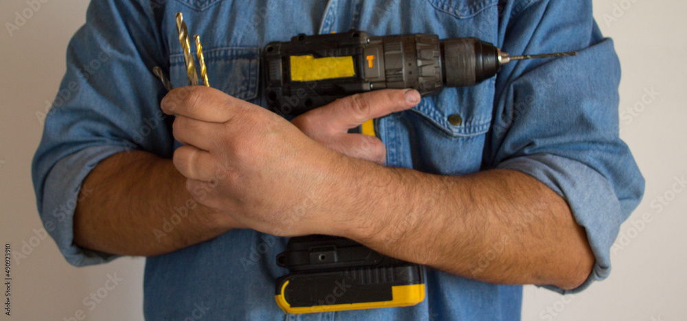 
Handyman man holding a screwdriver and drill bits. Craft projects at home. Horizontal banner