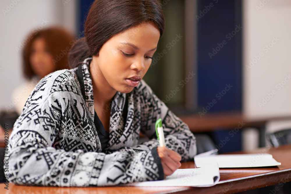 Nothing replaces hard work and diligent focus. Cropped shot of a student working diligently at her desk in class. Nothing replaces hard work and diligent focus. Cropped shot of a student working diligently at her desk in class.
