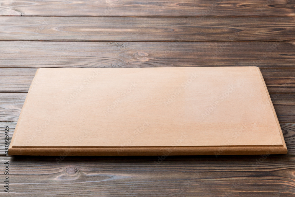 Perspective view of wooden cutting board on wooden background. Empty space for your design Perspective view of wooden cutting board on wooden background. Empty space for your design
