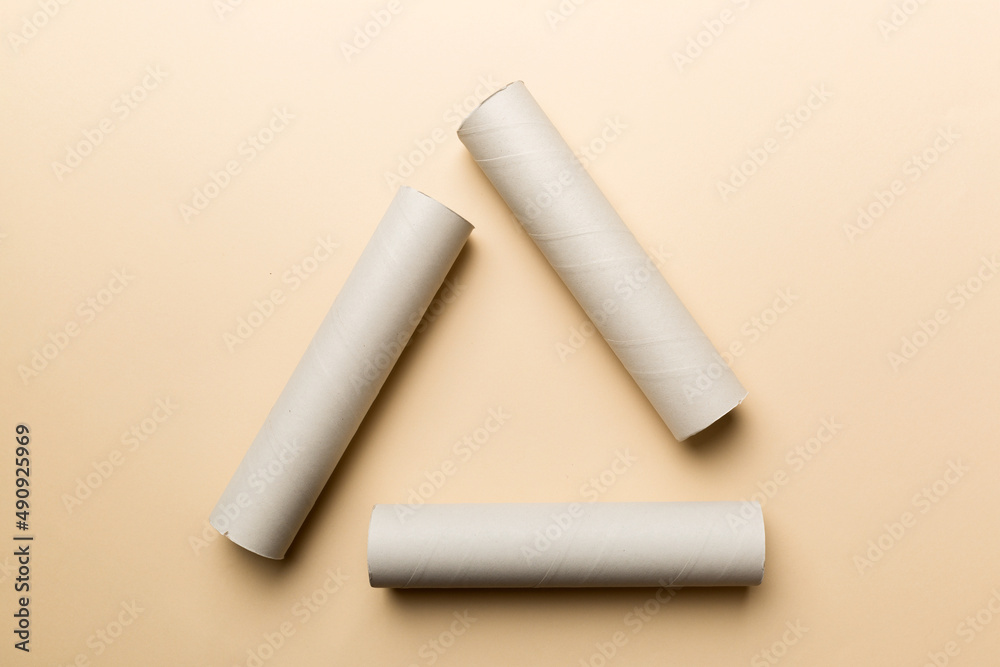 Empty toilet paper roll on colored background. Recyclable paper tube with metal plug end made of kraft paper or cardboard in the form of a recycling sign Empty toilet paper roll on colored background. Recyclable paper tube with metal plug end made of kraft paper or cardboard in the form of a recycling sign