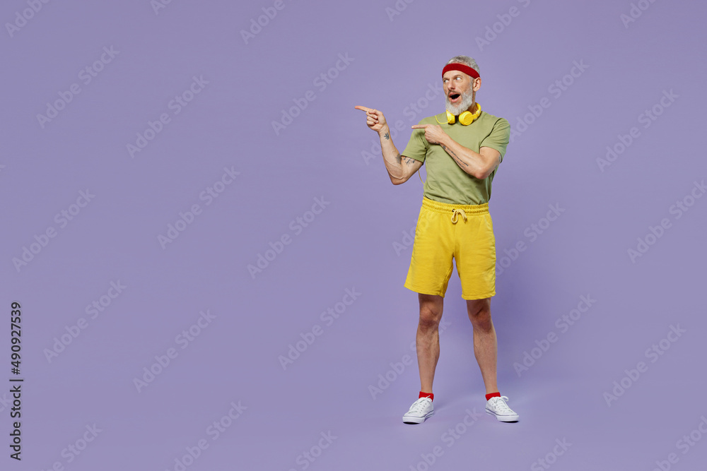 Full size body length elderly gray-haired bearded man 40s years old in headband khaki t-shirt point on workspace area copy space mock up isolated plain pastel light purple background studio portrait. Full size body length elderly gray-haired bearded man 40s years old in headband khaki t-shirt point on workspace area copy space mock up isolated plain pastel light purple background studio portrait.