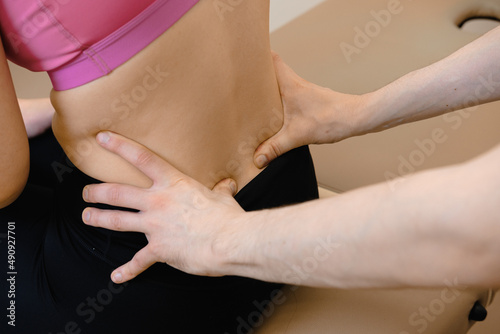 A chiropractor checks the girl's spine. Palpation of the back