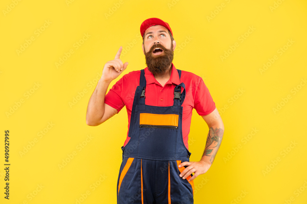 inspired bearded man mechanic in work clothes on yellow background