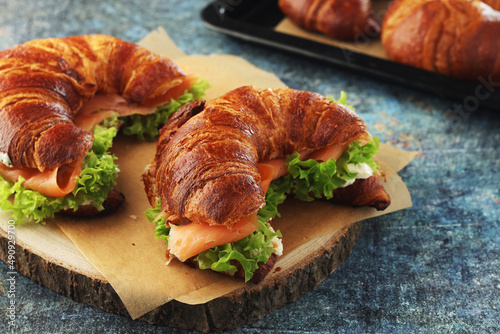 Freshly baked croissants with salmon and salad on the table