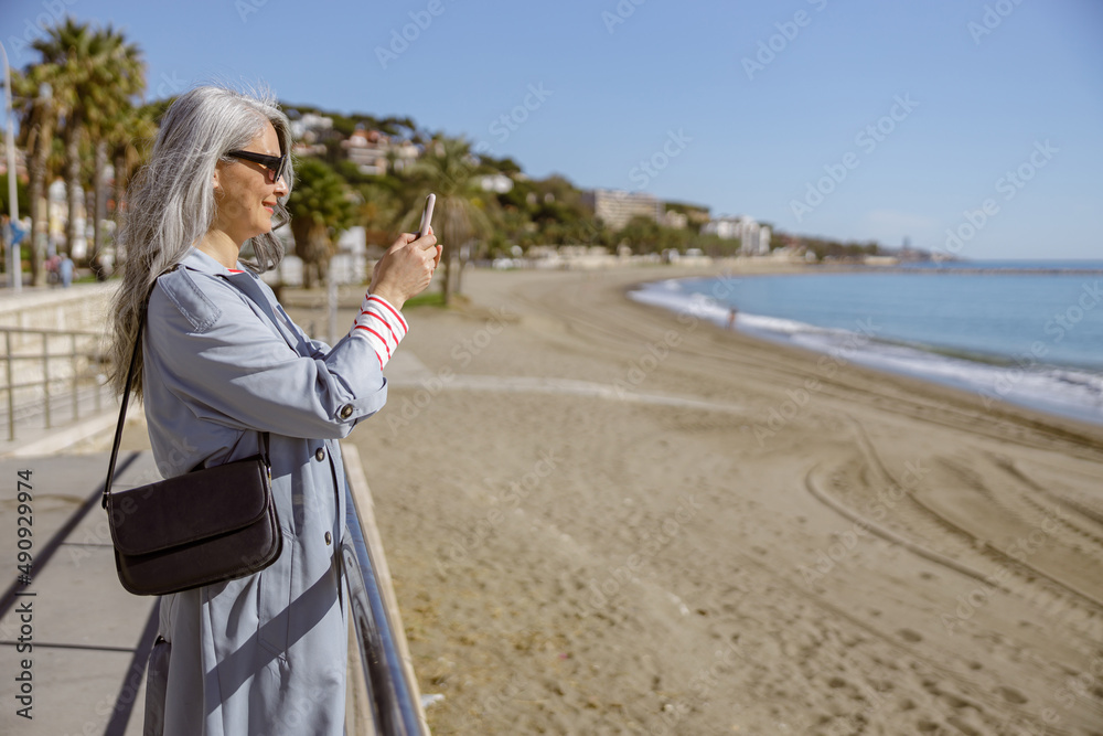 Urban lady taking pictures of beautiful coastline