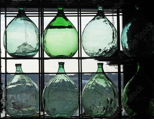 Large glass demijohns for wine against the light of a window photo