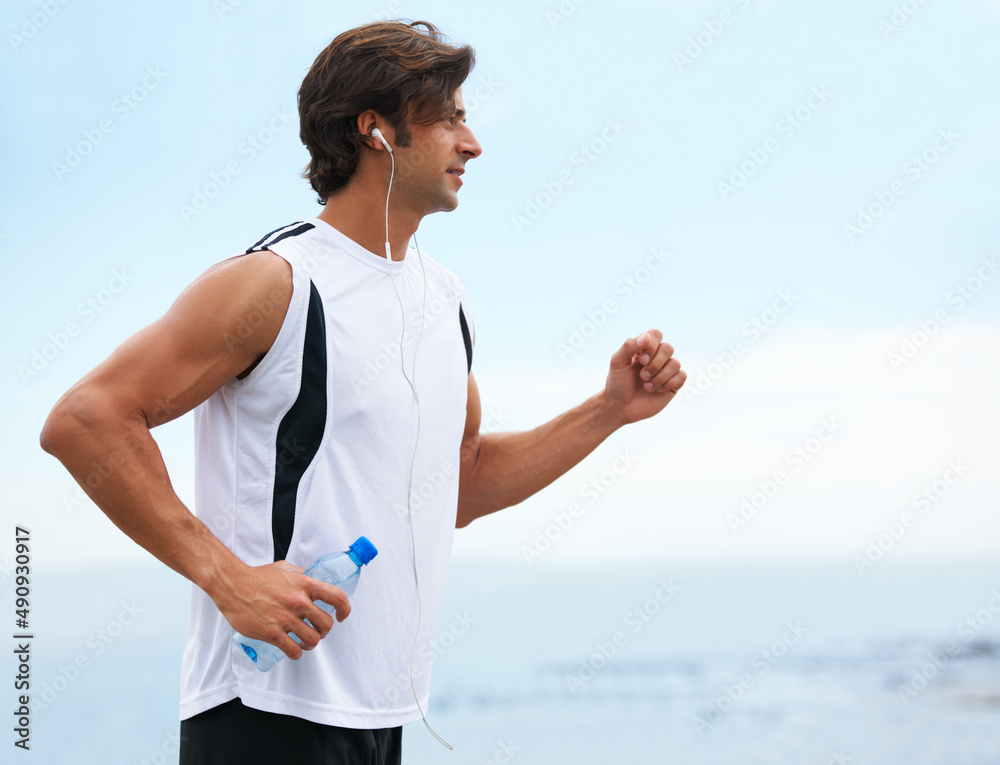 Nothing can hold him back. Profile view of a handsome man holding a water bottle, going for a run and listening to music - copyspace. Nothing can hold him back. Profile view of a handsome man holding a water bottle, going for a run and listening to music - copyspace.
