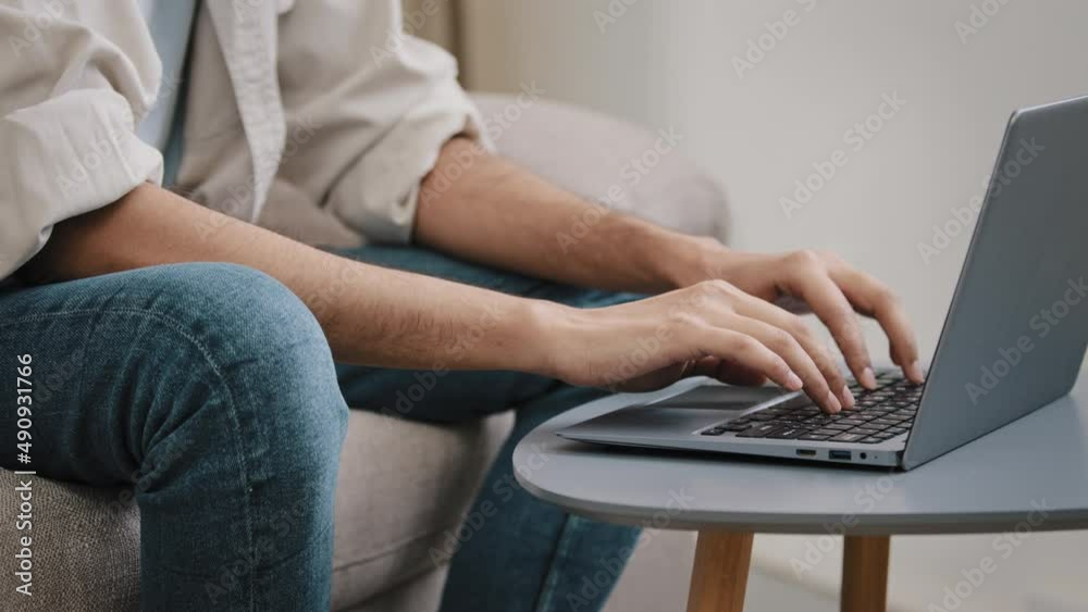Close-up male hands typing on laptop keyboard. Unrecognizable guy unknown business man in jeans casual shirt sitting on sofa with computer working chatting e-learning email answer online distant job Close-up male hands typing on laptop keyboard. Unrecognizable guy unknown business man in jeans casual shirt sitting on sofa with computer working chatting e-learning email answer online distant job