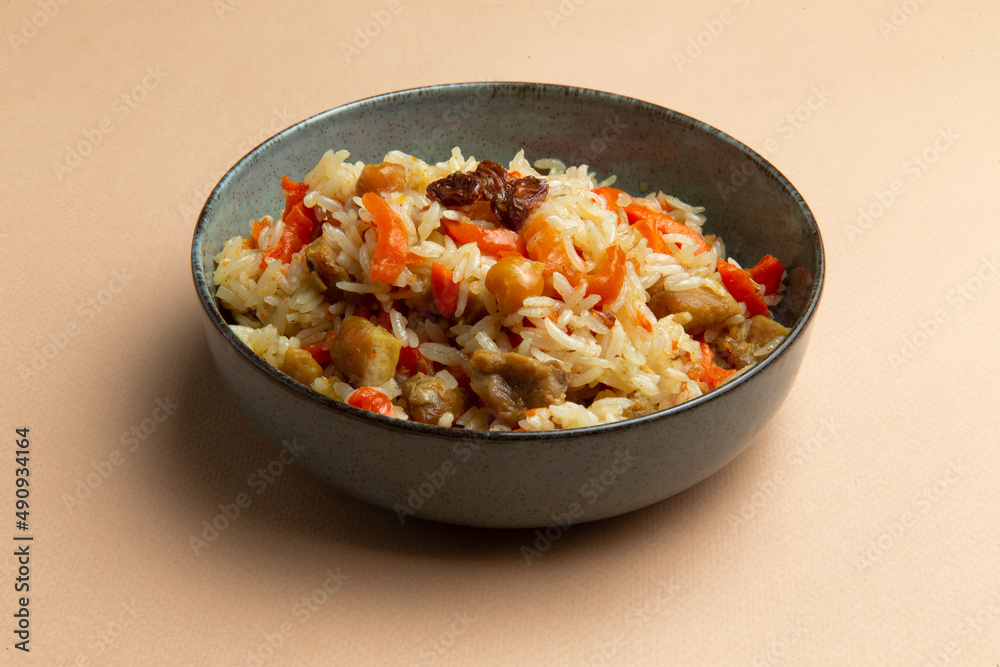 Traditional pilaf with chicken in a plate on a brown background. Traditional pilaf with chicken in a plate on a brown background.