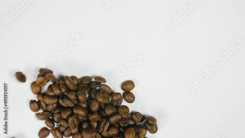 The coffee beans spin rotate quickly fast fly, dispart, splash to the sides with centrifugal coriolis force. The video is in reverse. Twist, create pattern, make design picture. Pressurized air wind. photo