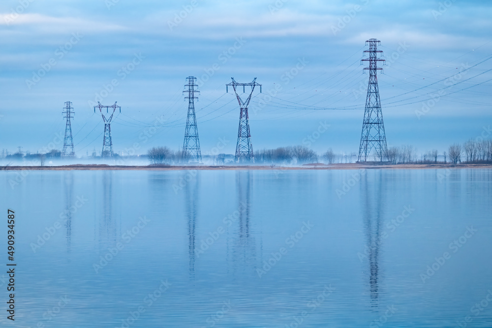 Pylones électrique à l'aube en réflections sur l'eau