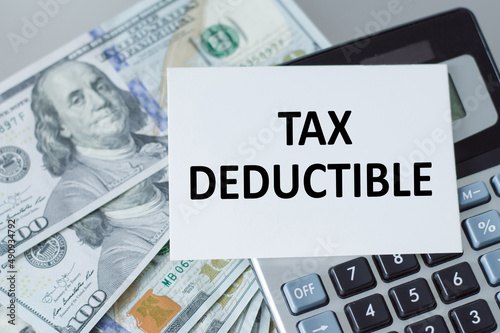 Word TAX DEDUCTIBLE on a business card on calculator. business and tax concept