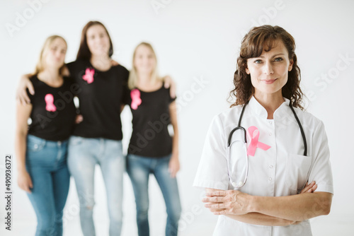 Young female doctor with pink bow standing in front of patients