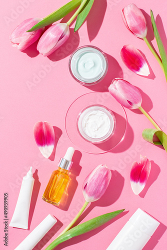 Spring cosmetic flat lay border with flowers on pink, copy space, top view. © Maria Shchipakina