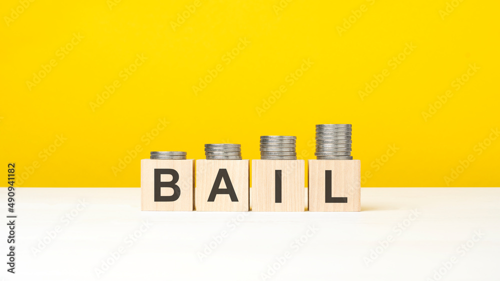 wooden cube on a white surface with text bail. yellow background wooden cube on a white surface with text bail. yellow background