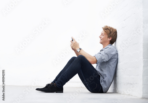 Sending an sms. A young man sitting in the studio and using his cellphone. photo